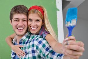 couple heureux peindre un mur dans une nouvelle maison photo