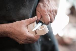 mains découpant une tasse en bois, travaillant avec un ciseau en gros plan. atelier en bois. processus de fabrication d'ustensiles de cuisine en bois photo