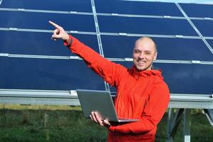 ingénieur utilisant un ordinateur portable sur le terrain de l'usine de panneaux solaires photo