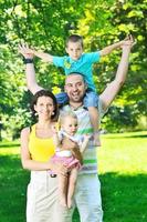 heureux jeune couple avec leurs enfants s'amuser au parc photo