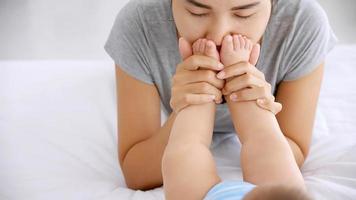 jeune mère embrassant les pieds de son bébé en dormant sur le lit. photo