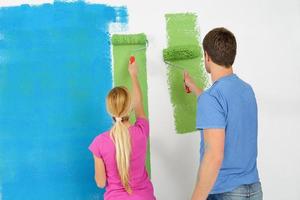 couple heureux peindre un mur dans une nouvelle maison photo