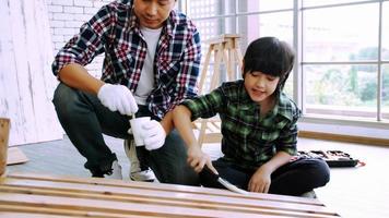 jeune charpentier masculin enseignant à son fils comment travailler le bois en atelier. photo