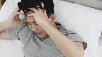 jeune homme souffrant de maux de tête allongé sur le lit à la maison photo