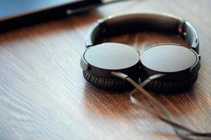 écouteurs sur la table de bureau. casque connecté à un ordinateur portable, espace de copie. écouter de la musique au travail photo