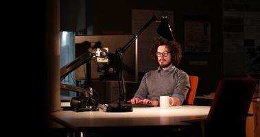 homme travaillant sur ordinateur dans un bureau sombre photo