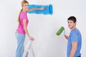 couple heureux peindre un mur dans une nouvelle maison photo