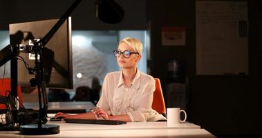 femme travaillant sur ordinateur dans un bureau sombre photo