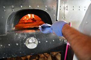 chef avec masque de protection contre les coronavirus préparant une pizza photo