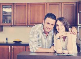 un jeune couple heureux s'amuse dans une cuisine moderne photo