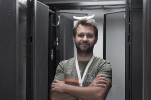 portrait d'un technicien masculin ou d'un administrateur réseau debout courageux comme un héros avec les bras croisés dans la salle des serveurs du centre de données. photo