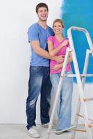 couple heureux peindre un mur dans une nouvelle maison photo