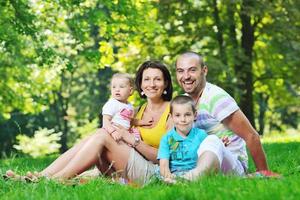 heureux jeune couple avec leurs enfants s'amuser au parc photo