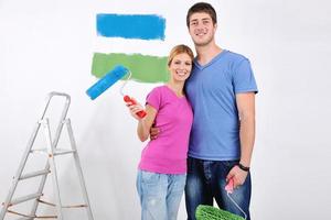 couple heureux peindre un mur dans une nouvelle maison photo