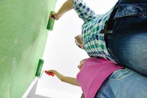 couple heureux peindre un mur dans une nouvelle maison photo