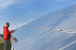 ingénieur utilisant un ordinateur portable sur le terrain de l'usine de panneaux solaires photo