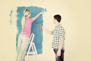 couple heureux peindre un mur dans une nouvelle maison photo