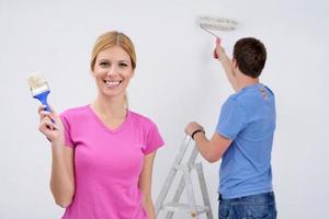 couple heureux peindre un mur dans une nouvelle maison photo