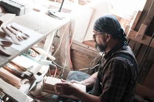 maître cuillère dans son atelier avec des produits en bois et des outils sélectionnant le bon bois pour fabriquer des ustensiles de cuisine en bois. photo