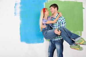 couple heureux peindre un mur dans une nouvelle maison photo