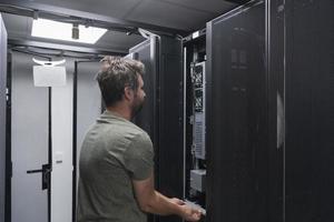 ingénieur informatique travaillant dans la salle des serveurs ou le centre de données, le technicien met dans un rack un nouveau serveur de superordinateur central d'entreprise ou de ferme minière de crypto-monnaie. photo