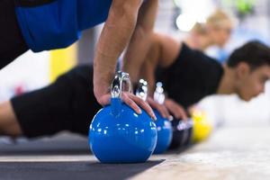 jeunes athlètes faisant des pompes avec des kettlebells photo