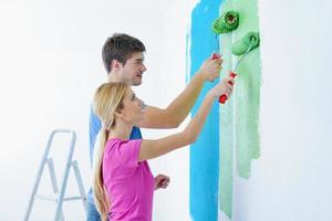 couple heureux peindre un mur dans une nouvelle maison photo