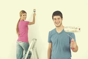 couple heureux peindre un mur dans une nouvelle maison photo