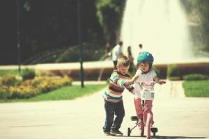 garçon et fille dans le parc apprenant à faire du vélo photo