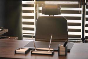 lieu de travail de bureau d'affaires. la lumière du soleil sur le lieu de travail pour le chef, le patron ou d'autres employés. table et chaise confortable. lumière à travers les stores à demi ouverts photo