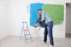 couple heureux peindre un mur dans une nouvelle maison photo