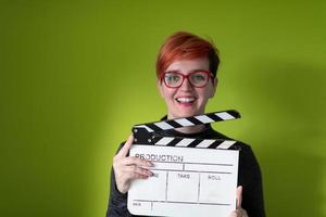 redhead woman holding movie clapper sur fond vert photo