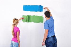 couple heureux peindre un mur dans une nouvelle maison photo