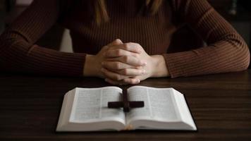 femme assise et étudiant les écritures.la croix de bois dans les mains. concepts d'éducation chrétienne les saintes écritures s'ouvrent et prient dieu. photo