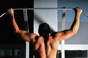 jeune homme aux bras forts travaillant dans une salle de sport photo