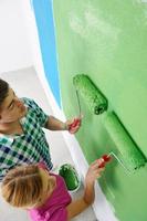 couple heureux peindre un mur dans une nouvelle maison photo