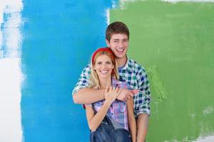 couple heureux peindre un mur dans une nouvelle maison photo