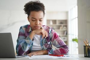 étudiante biraciale concentrée étudiant la préparation à l'examen faisant ses devoirs à la maison. l'enseignement à distance photo