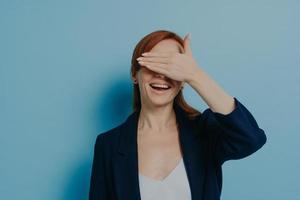 Ginger girl drôle ludique couvrant ses yeux avec palm isolé sur fond bleu, isolé sur bleu photo