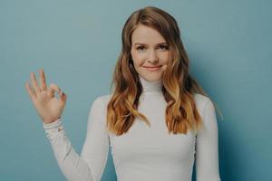 joyeuse jeune femme européenne montrant un geste correct isolé sur un mur de studio bleu pastel photo