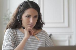 l'entrepreneur concentré dans les écouteurs écoute attentivement le vebinar éducatif en regardant l'écran de l'ordinateur portable photo