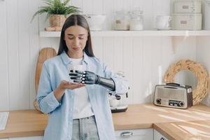 jolie fille handicapée tient soigneusement une tasse de thé avec une main cybernétique. concept de capteurs de préhension. photo