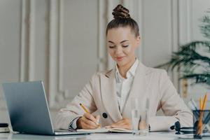 séduisante femme d'affaires réussie en costume élégant faisant la liste des choses à faire au travail photo