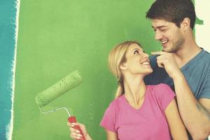 couple heureux peindre un mur dans une nouvelle maison photo