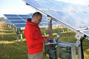 ingénieur utilisant un ordinateur portable sur le terrain de l'usine de panneaux solaires photo