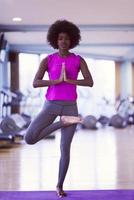 femme afro-américaine faisant du yoga dans la salle de sport photo