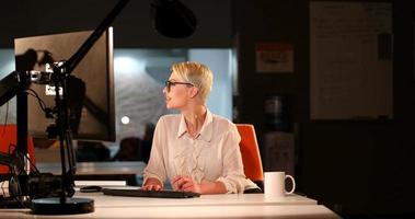 femme travaillant sur ordinateur dans un bureau sombre photo