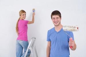 couple heureux peindre un mur dans une nouvelle maison photo