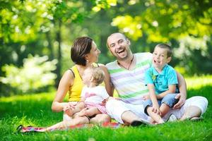 heureux jeune couple avec leurs enfants s'amuser au parc photo