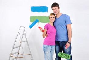 couple heureux peindre un mur dans une nouvelle maison photo